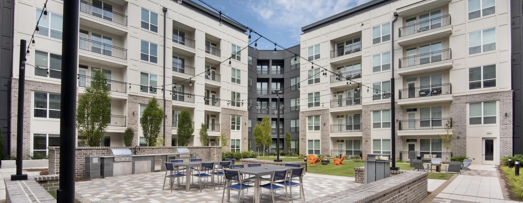 a courtyard with tables and chairs and buildings in the background